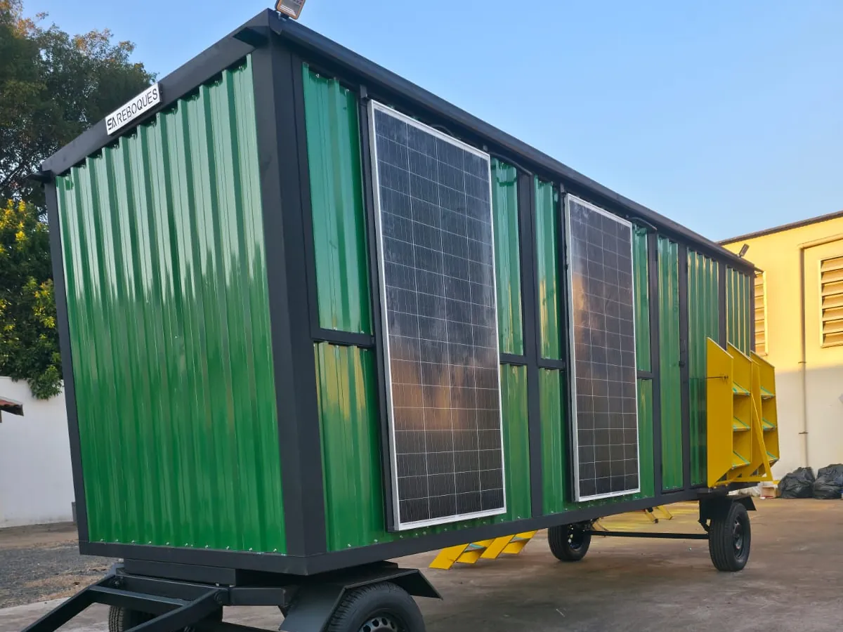 Detalhe dos painéis solares fixados na lateral verde da unidade, reflexos do fim de tarde