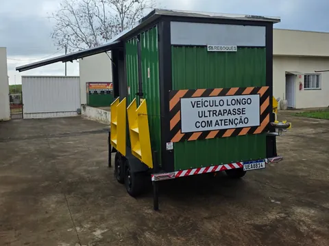 Unidade verde com plataforma elevatória, escadas amarelas e placa de sinalização na traseira