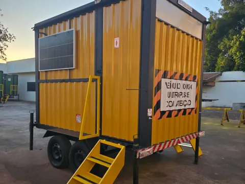 Unidade amarela compacta com painel solar e escadas, placa de advertência na lateral