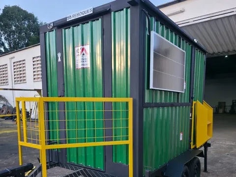 Unidade verde longa com painéis solares e guarda-corpo amarelo, em ângulo no pátio