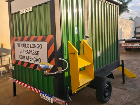 Unidade verde com lava-olhos na lateral e placa de advertência, escadas amarelas ao lado