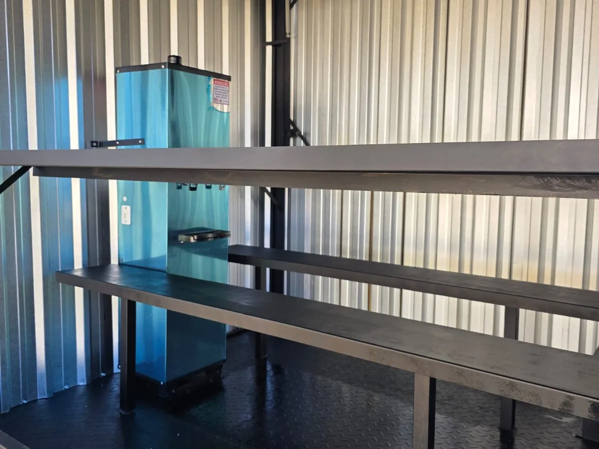 Bebedouro azul e bancada de aço no interior da unidade, forro e paredes metálicas
