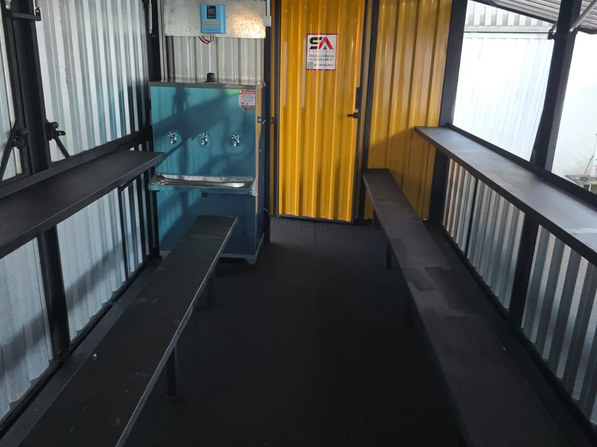 Interior da área de vivência com bancos e espaço para refeições